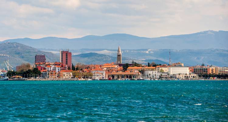 Horizon d'une ville côtière avec des clochers d'église et des montagnes en arrière-plan.