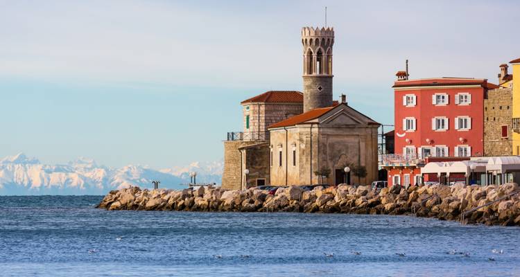 Ville côtière avec une église dotée d'un clocher et des bâtiments colorés.