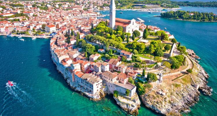 Vue aérienne panoramique d'une ville côtière avec un clocher d'église proéminent.