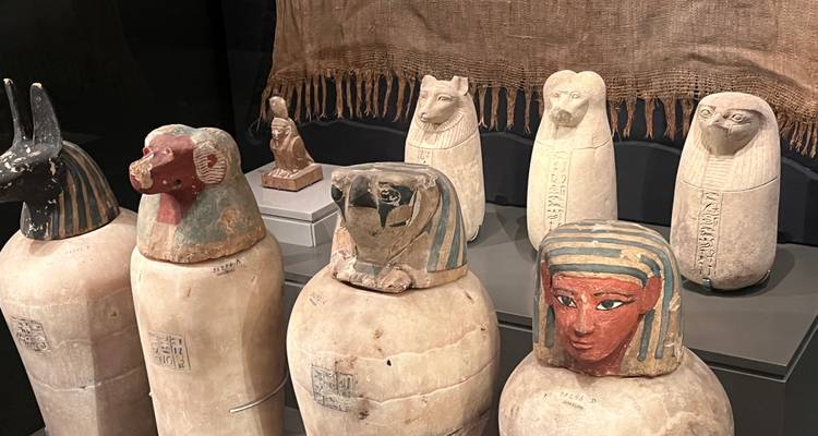 Sammlung von Kanopenkrügen mit anthropomorphen Deckeln in einem Museum.