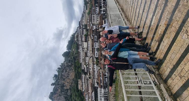 Grupo de personas paradas en un puente con edificios tradicionales en el fondo.