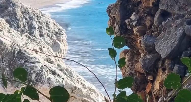 Playa con acantilados escarpados y agua azul del océano.