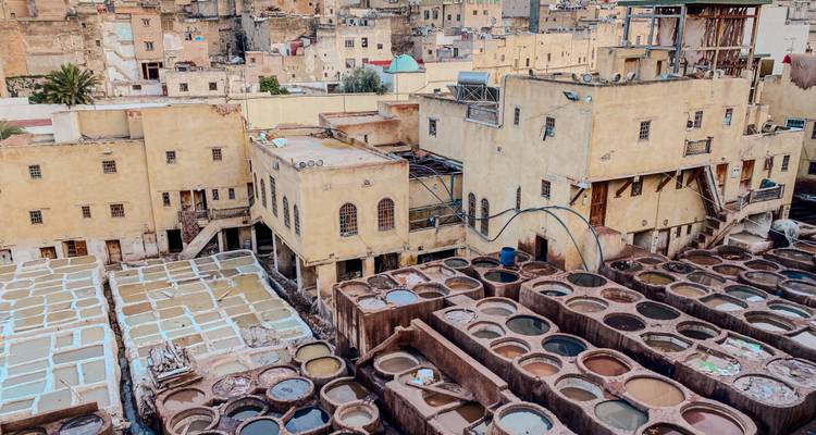 Zicht op traditionele leerlooierij met bassins in een historische stad.