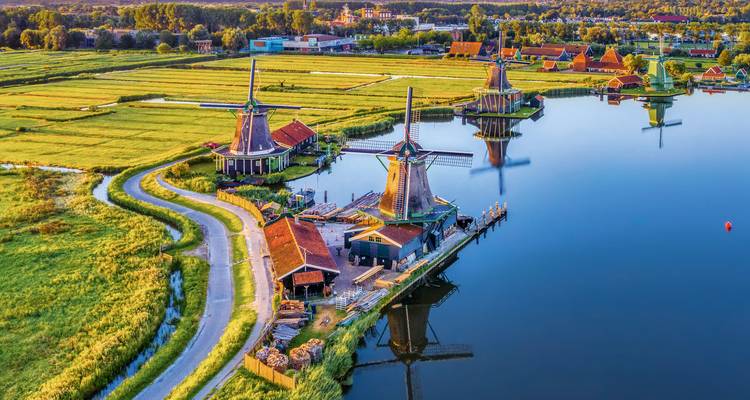 Molinos de viento and campos verdes junto a un río vistos desde arriba.