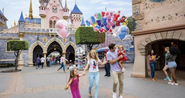 Familie in een pretpark, ballonnen vasthoudend bij een kasteel.