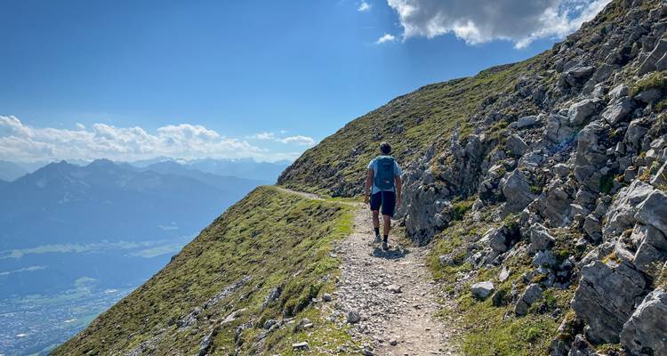Personne faisant de la randonnée le long d'un sentier de montagne avec des vues panoramiques.