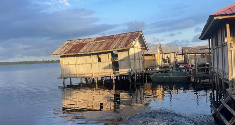 Stelzenhäuser über dem Wasser unter einem teilweise bewölkten Himmel.