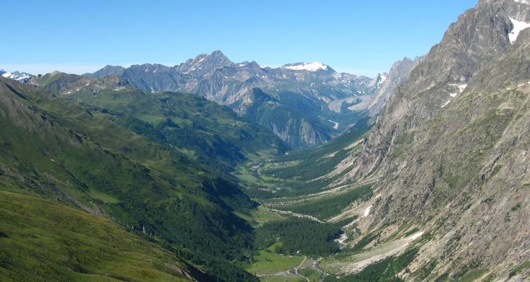 Vista amplia de un valle verde entre altas cordilleras montañosas.