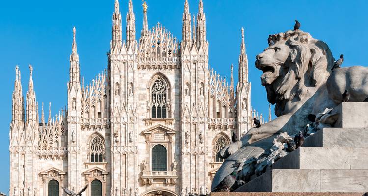 Gros plan de la façade ornée en marbre blanc du Duomo de Milan avec une sculpture de lion rugissant.