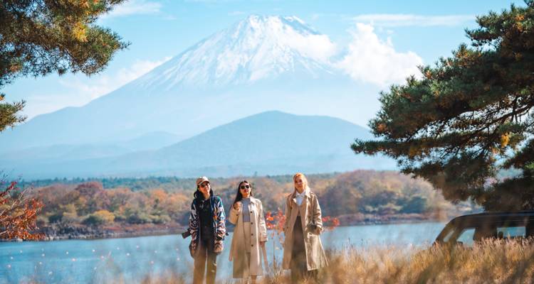 Drie vrouwen voor de berg Fuji met uitzicht op een schilderachtig meer.