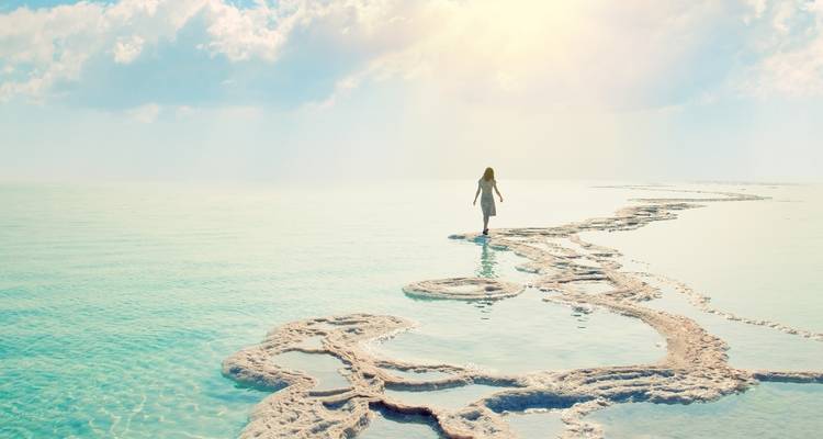 A person walking on a salt formation in the Dead Sea, with a serene atmosphere.