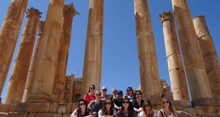A group of people posing in front of the ancient ruins in Jerash, Jordan.