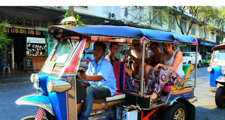 Des touristes voyageant dans un tuk-tuk coloré dans une rue animée de la ville.