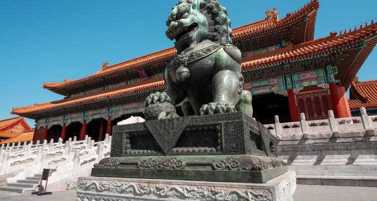 Bronzelöwenstatue mit traditioneller chinesischer Architektur im Hintergrund
