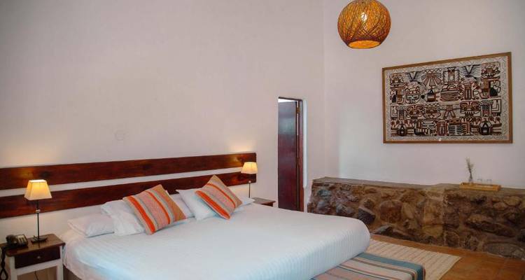 Chambre d'hôtel avec un grand lit, des lampes et une tapisserie décorative.