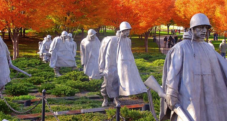 Stalen soldatenbeelden van het Korean War Veterans Memorial omringd door vurige herfstgebladerte.