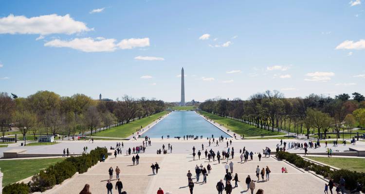 Uitzicht over de Reflecting Pool naar het Washington Monument met veel bezoekers die over de National Mall wandelen.