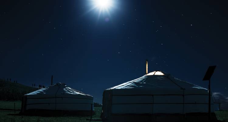 Deux yourtes brillent doucement sous un ciel nocturne mongol rempli d'étoiles illuminé par une lune éclatante