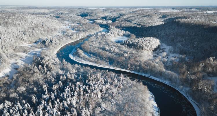 Vue aérienne d'une vallée enneigée avec une rivière sinueuse.