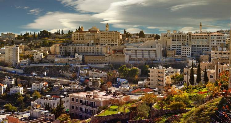 Colorful hill town with historic buildings beneath streaked clouds