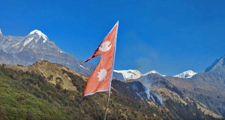 Drapeaux népalais avec en toile de fond des sommets enneigés et un ciel bleu.