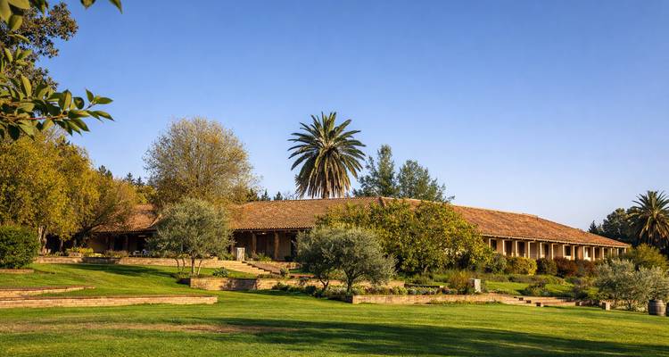 Gran edificio rodeado de árboles y césped bajo un cielo despejado.