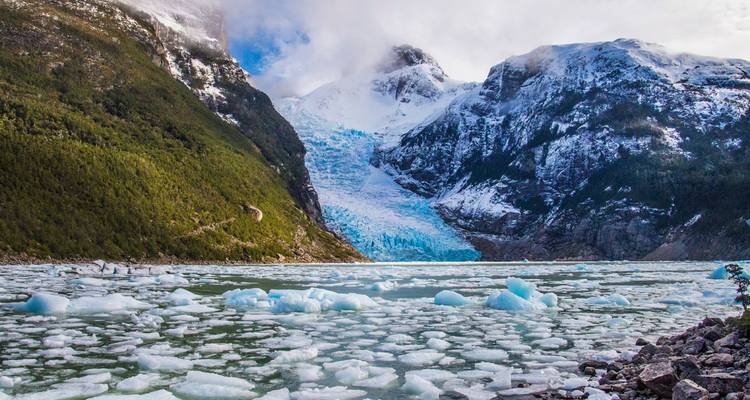 Valle glacial con trozos de hielo azul flotando en una laguna color turquesa lechoso enmarcada por montañas nevadas