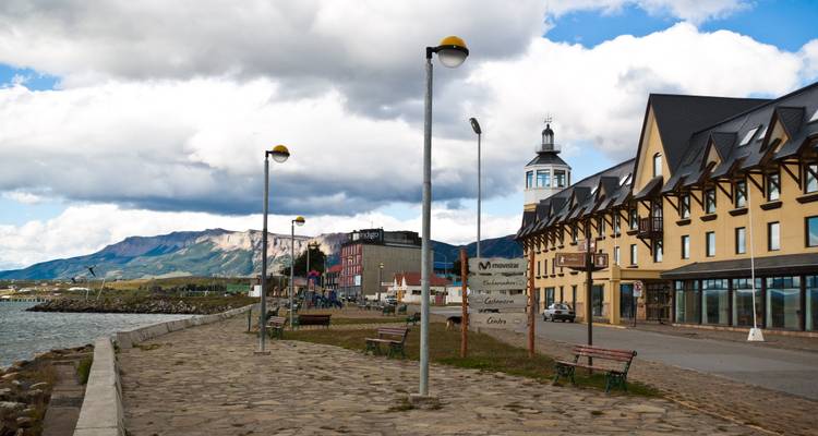 Paseo junto al mar con bancos y edificios de estilo tradicional en un pequeño pueblo de la Patagonia