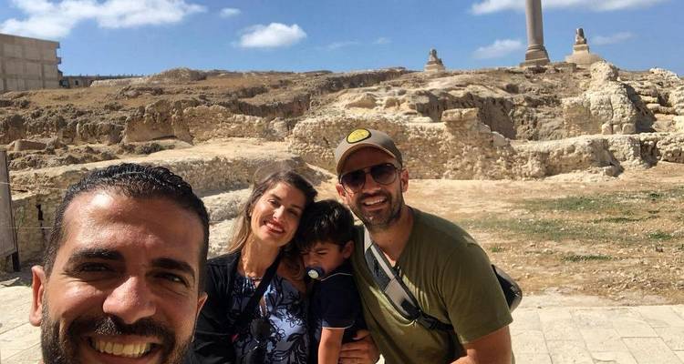 Una familia con un niño posando frente a un sitio histórico con ruinas antiguas.