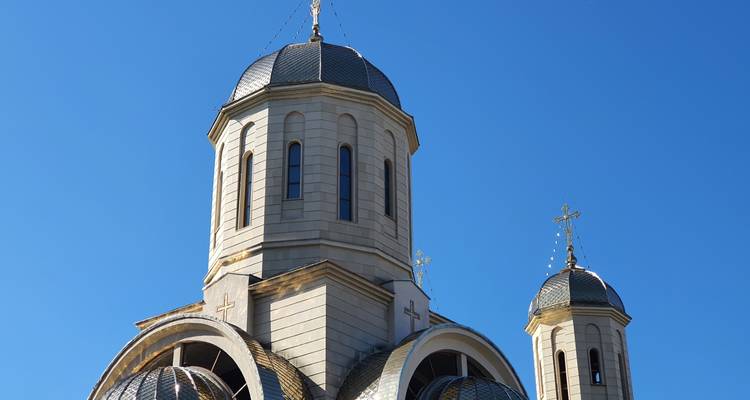 Close-up van moderne orthodoxe kerkkoepel en klokkentoren tegen een heldere blauwe hemel.