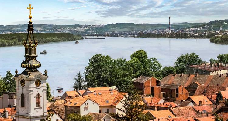 Panorama del río Danubio con torre de iglesia y edificios de techos rojos de Novi Sad a lo largo de la orilla.
