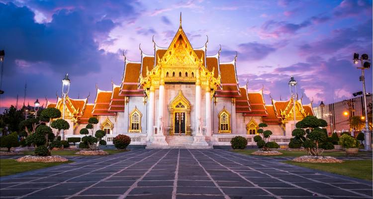 Twilight view of Bangkok’s Marble Temple glowing under a vibrant purple sky.