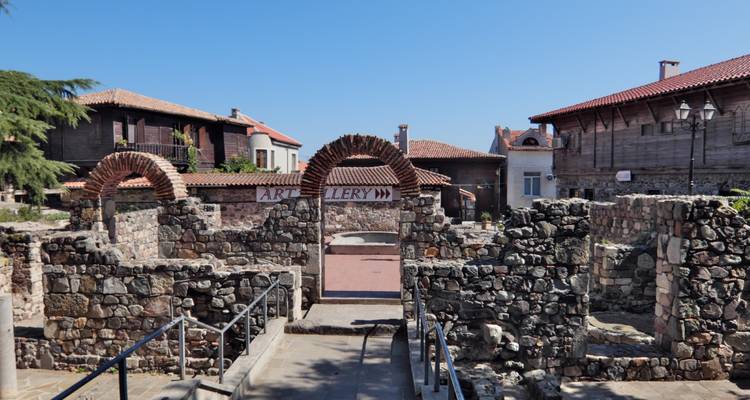 Ruinas de piedra con arcos y muros antiguos sobre un cielo azul despejado