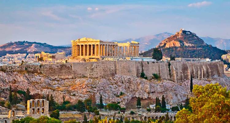 Iconic Parthenon atop the Acropolis hill in Athens glowing in late afternoon light with Mount Lycabettus behind