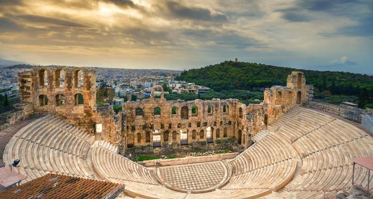 Stone tiers of the ancient Odeon of Herodes Atticus amphitheatre overlooking Athens under dramatic skies