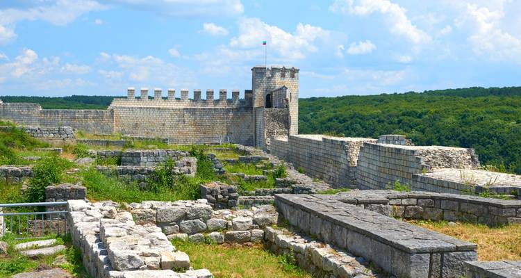 Ruines d'une ancienne forteresse sur une colline avec un ciel bleu au-dessus.
