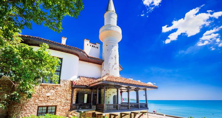 Bâtiment historique avec minaret au bord de la mer.
