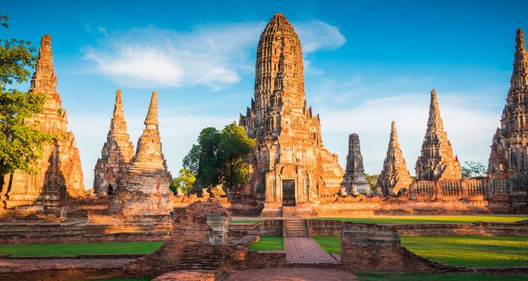 Torres históricas de ladrillo y prangs del Wat Chaiwatthanaram resplandeciendo bajo la cálida luz del atardecer.