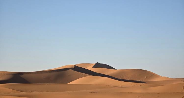 Gladde gouden zandduinen onder een heldere blauwe ochtendlucht