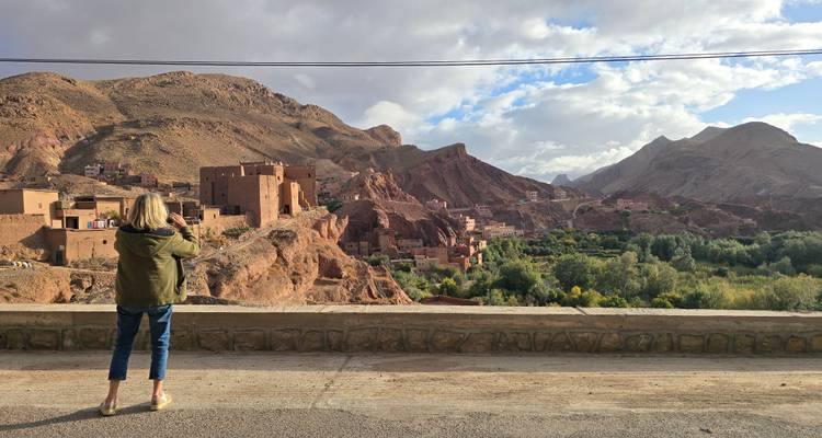 Viajero fotografiando un pueblo de terracota enclavado entre colinas rojas espectaculares