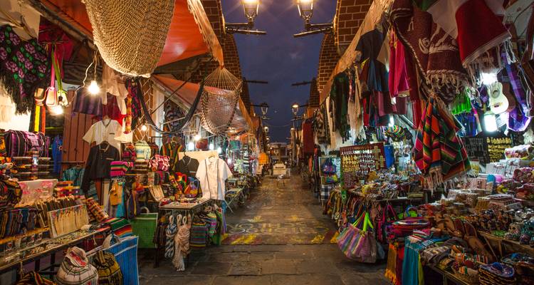 Calle de mercado de artesanías vibrante al atardecer iluminada por cálidas linternas.