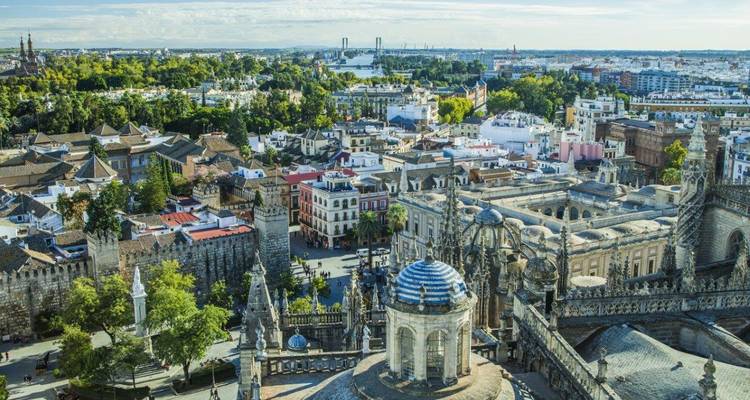 High aerial view of Seville’s historic quarter with rooftops, parks and landmarks stretching to the horizon.