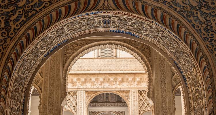 Intricately carved Moorish arches and stucco patterns inside the Alcázar of Seville.
