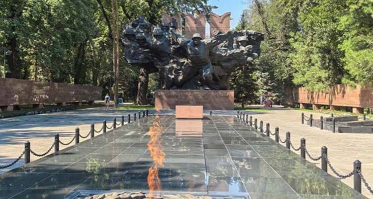 Llama eterna y monumento en un entorno de parque tranquilo.