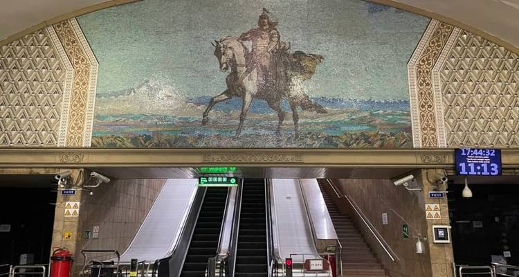 Mural de mosaico que representa un guerrero con escaleras mecánicas en una estación de metro.