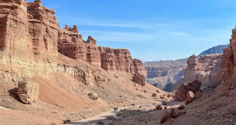 Excursionistas caminando a través de un cañón de roca roja.