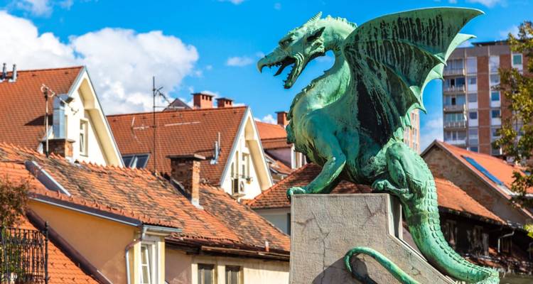 Estatua de dragón en una plaza de la ciudad con edificios en el fondo.