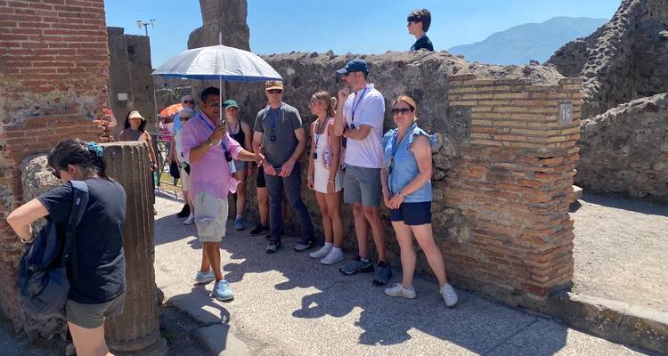 Groupe de personnes lors d'une visite guidée autour de ruines antiques.