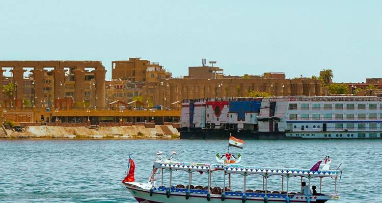 Barco en un río con una ciudad antigua al fondo.