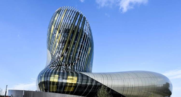 Edificio de museo futurista de vidrio curvado reflejando la luz del sol contra un cielo azul.